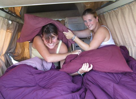 Two girls pillow fighting in back of Travelwheels Cheap campervan hire Sydney