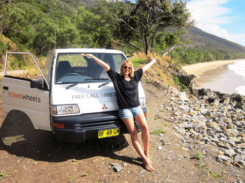 Photo of Sara in front of our 2 person campervan by the beach