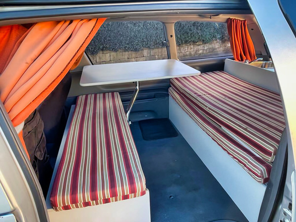 Photo showing the lounge area with two benches and table inside a used Toyota automatica camper for sale