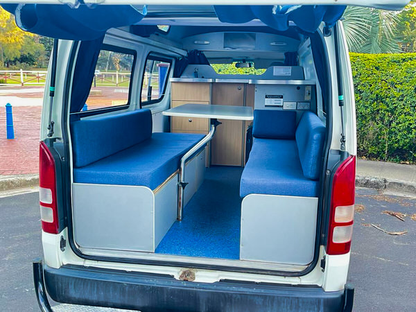 Used Campervan for sale in Sydney - Photo showing a kitchen area in the back of a Toyota Hiace Campervan with two comfortable benches and a removable table