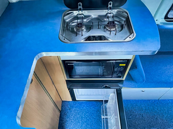 Used Campervan for sale in Sydney - Photo showing a kitchen area in the back of a Toyota Hiace Campervan with two burners stove and plenty of worktop space