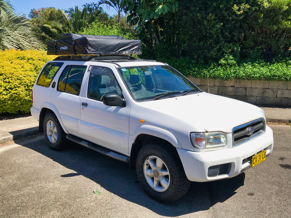 Roof Top Tent 4x4 for sale in Sydney - Model shown is a Automatic Nissan Pathfinder in white - photo showing the front drivers side angle view with roof tent closed