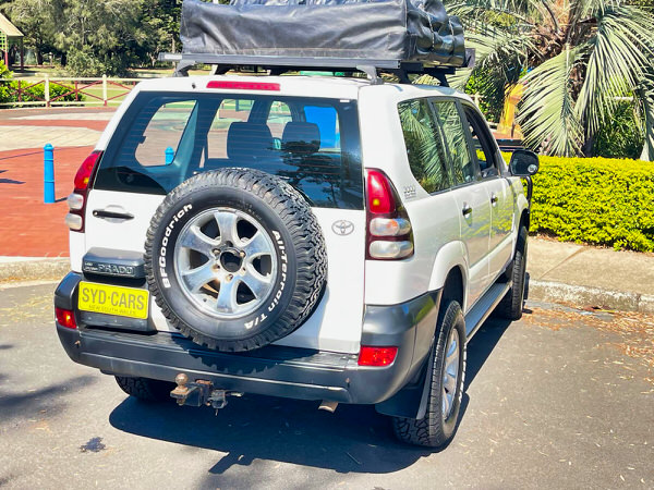 Used Toyota Prado for Sale - Manual 2008 Turbo Diesel Model with heavy duty Roo bars and roof rack + Roof Top Tent - photo showing the rear driver side angle view with roobars and the roof top tent folded away