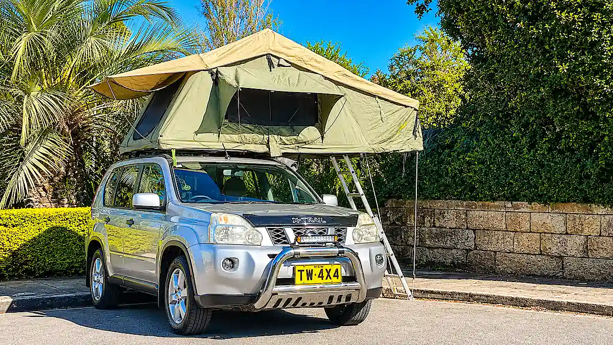 Used Nissan 4x4 for sale at Travelwheels Campervans in Sydney - photo shows front view with roof tent open and ladder